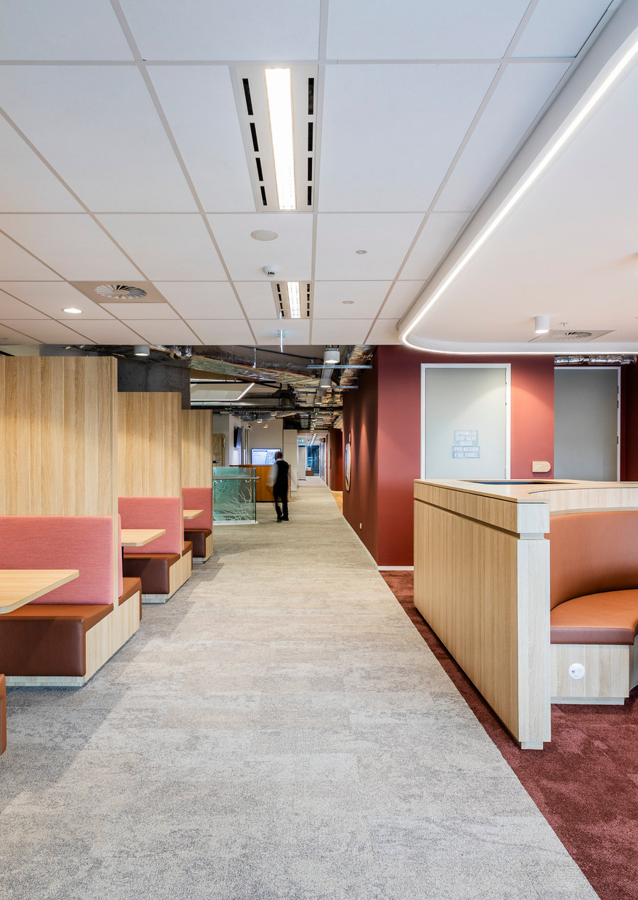 Workplace breakout area with banquette seating, feature partitions and suspended tile grid ceiling with linear diffusers