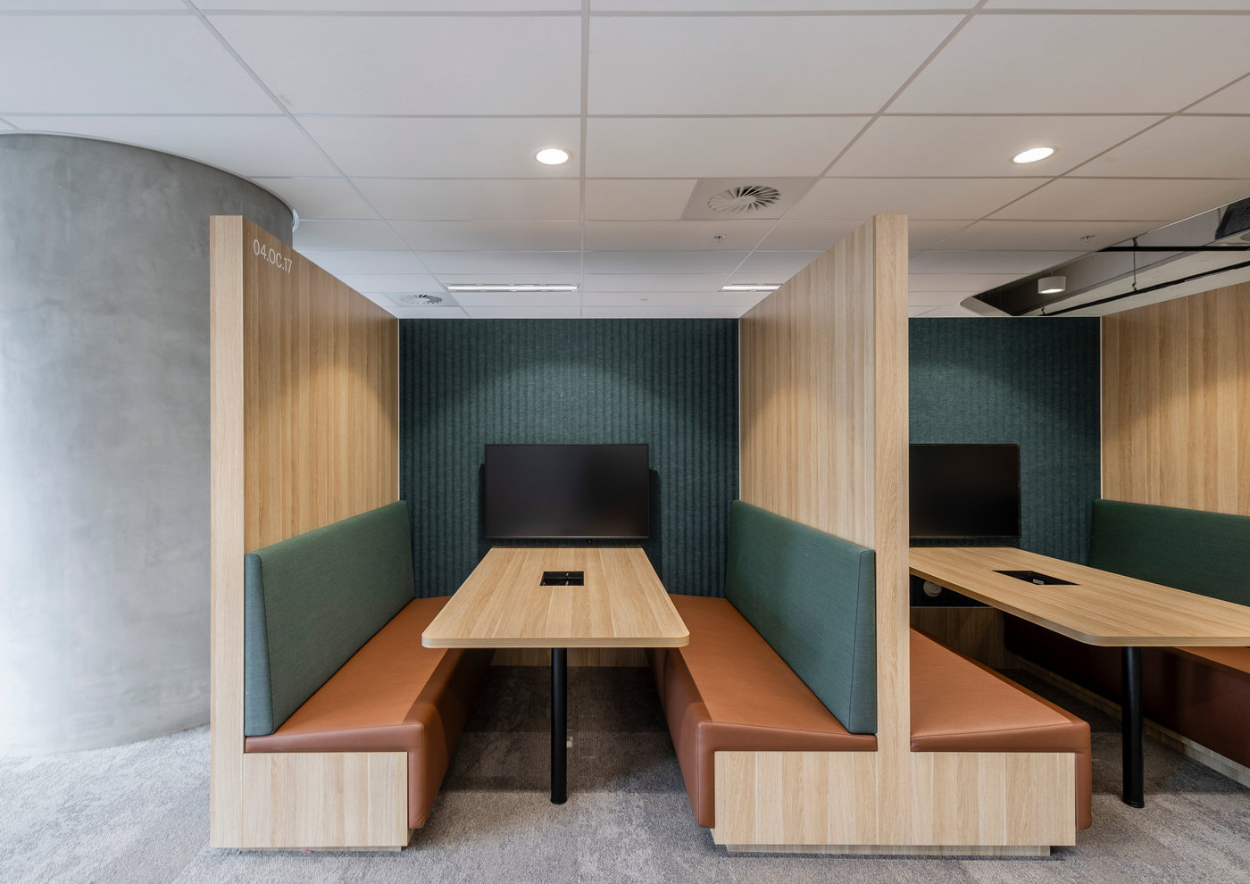 Timber meeting booths with dark green acoustic wall panelling beneath a suspended mineral fibre tile ceiling
